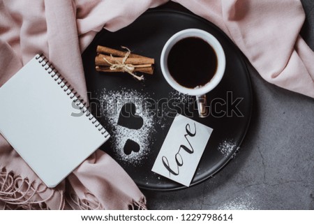 Valentines day background. Cup of coffee, notebook,  scarf, cinnamon and heart on gray table. Valentines and Mother's Day concept. Flat lay, top view, copy space