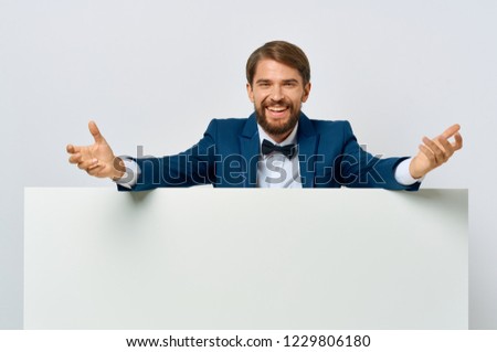 Happy man in a suit behind a white sheet of paper                    