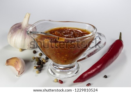 Sauceboat of spicy adjika sauce. Arabic and Caucasian cuisine. Ethnic food on white background. Royalty-Free Stock Photo #1229810524