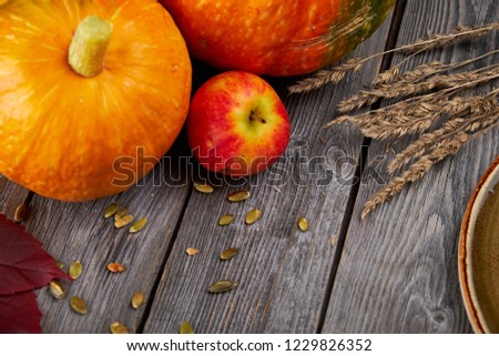 Autumn harvest Thanksgiving pumpkins, apples, wheat ears and fallen leaves on wooden background. Seasonal Fall Food