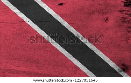 Flag of Trinidad and Tobago on wooden plate background. Grunge Trinidadian flag texture, A red field with a white-edged black diagonal band. 