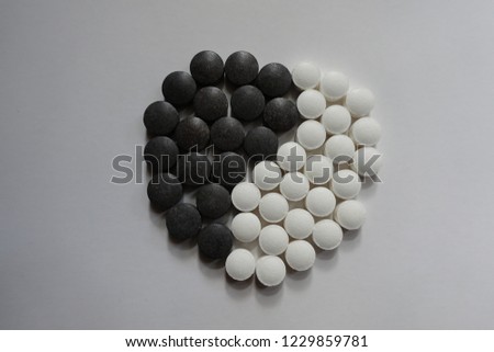 White and black pills in shape of yin and yang symbol from above