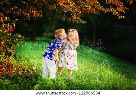 Adorable happy kids outdoors on summer day, little boy kissing a girl