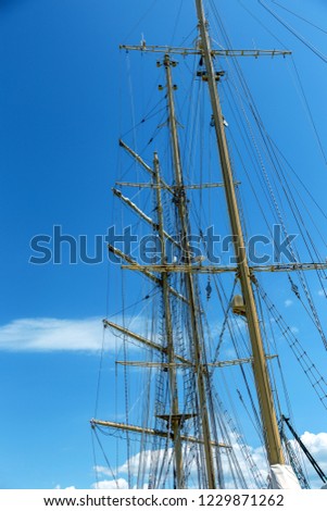 Close-up of a mast on traditional sailboats. The mast of large wooden ship. Beautiful travel picture with masts and rigging of sailing ship against blue orange sky. Background for tourist advertising
