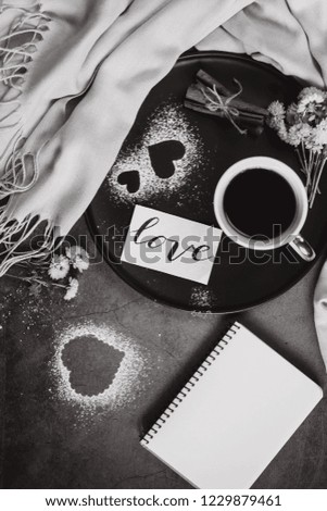Valentines day.  Cup of coffee, notebook, scarf, flower, cinnamon and heart on gray table from above in flat lay style.