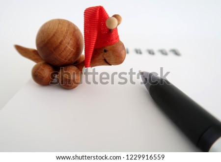 Christmas Holiday inspiration- a cute wooden turtle wearing Christmas hatwith  a notebook and a pen , on white background