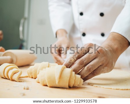 Young pastry chef making some croissant in the bakery. Royalty-Free Stock Photo #1229933578