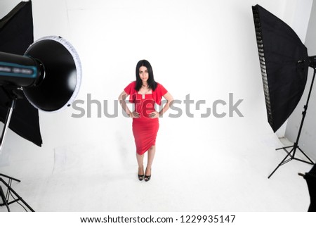 girl with red dress poses in studio on white