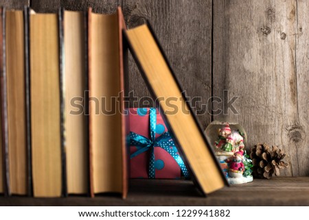 A gift hidden on a wooden shelf behind the books.