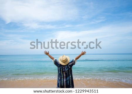 happy travel woman stand on sand of the sea with blue sky at sunny day. subject is blurred.
