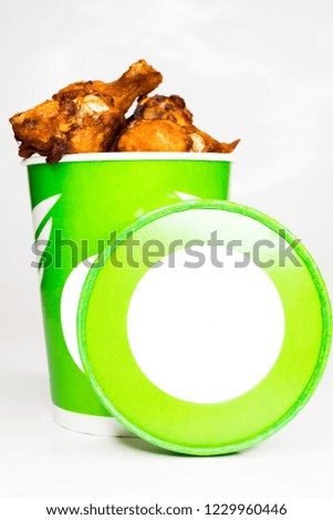 Fried chicken wings with sauce in paper packaging.