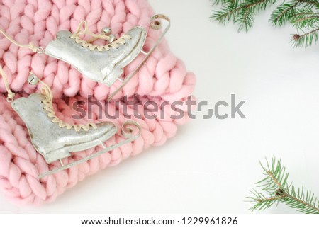 The skates on the Christmas tree on a pink woolen plaid on a white background, decorated with green fir branches. Winter mood. New Year's and Xmas.
