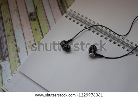 Notepad for sketches next to headphones on a colored background