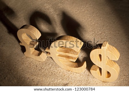 Wooden economy and currency unit's shadow on sand
