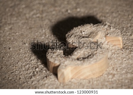 Wooden economy and currency unit in sand with shadow