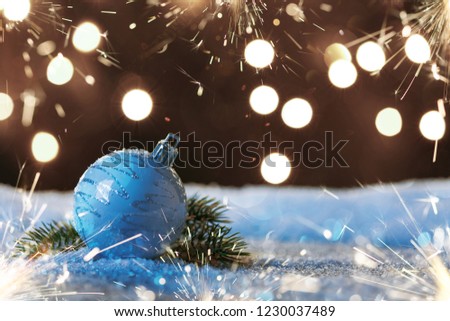 Christmas ball with sparklers and garlands on the snow. New Year's card