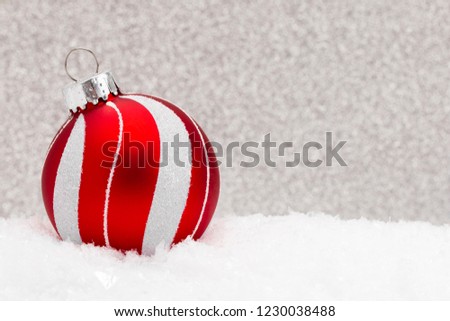 A Christmas Ornament in the Snow with a Glittery Background