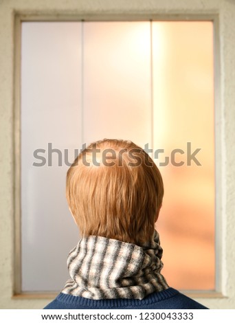 Back view of man looking at window or picture in a frame and thinking