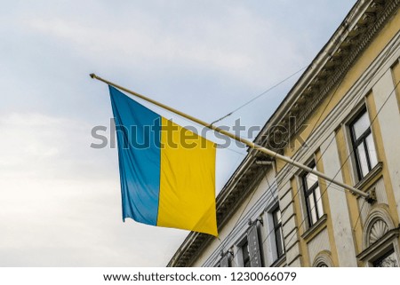 Flag of Ukraine, waving on wind, fixed to old tenement house in Lviv. 