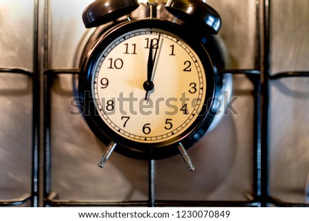Cooking time concept. Black alarm clock on a kitchen stove.