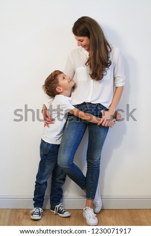 Pretty young mother with son hugging on white background