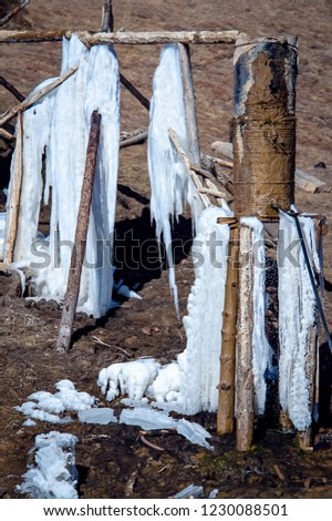 Frozen rustic water tank and wooden pipe bursts in country field in winter day, Tibetan plateau.