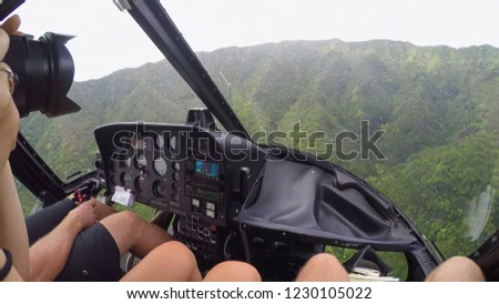 AERIAL: Tourist on a helicopter tour taking pictures. Helicopter flying towards stunning vast mountain range in tropical rain. Magnificent view from copter flying above lush green jungle.