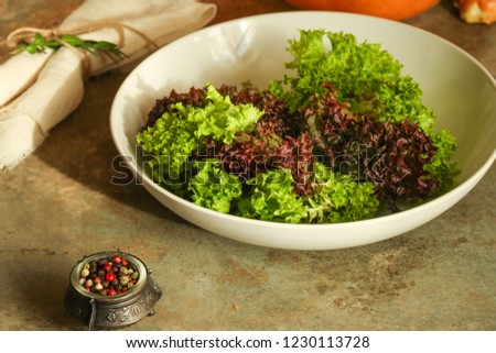 fresh lettuce leaves

salad in a white plate on a wooden table background. top view. copy space
