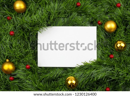 Creative Christmas layout. White card with copy space on green tinsel. Red and golden balls. Border arrangement. Flat lay top view.