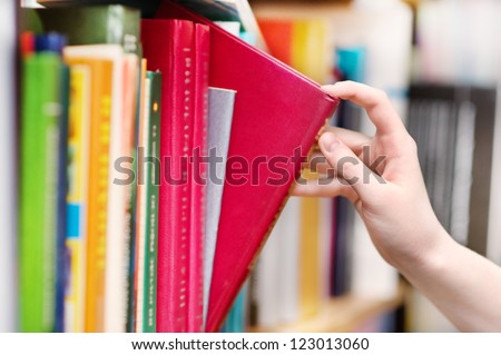 closeup  hand selecting book from a bookshelf Royalty-Free Stock Photo #123013060