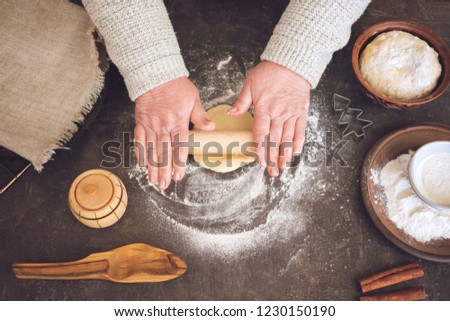 Process of making christmas cookies. Mature woman,  granny hands making dough.  Ingredients for baking pie: flour, pastry, crockery, kitchen utensils, fir tree cookie figure on dark background.