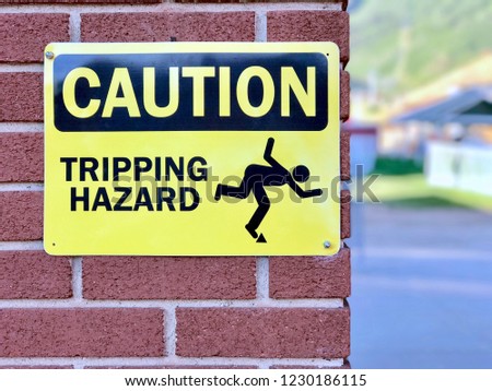 yellow sign saying "Caution Tripping Hazard" with illustration of person tripping