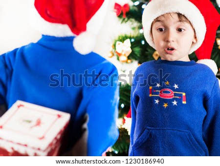 Two children boys brothers give each other gifts for Christmas and New year emotionally surprised