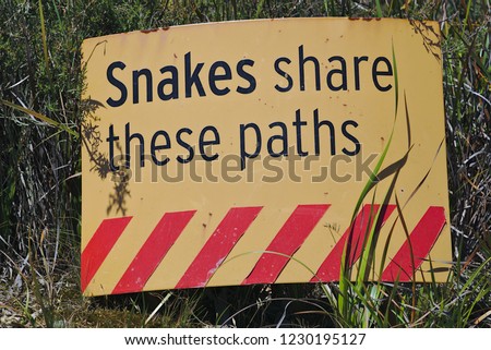 Snakes share these paths warning sign in yellow color with red diagonal stripes