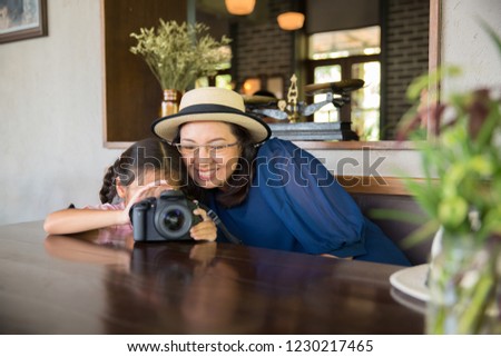 Mother and daughter enjoy using camera to take photo, family travel concept
