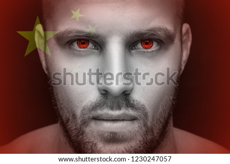 Portrait of a young serious man, in whose eyes the reflected national flag of China, against an isolated black background and flag