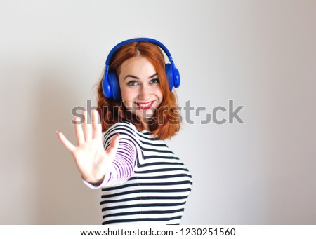 Fashion pretty girl listening to music in headphones wearing a striped sweater. Music, lifestyle concept.