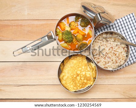 Antique stainless steel food carrier (Tiffin food container) and spoon on wood table. Omelette (Omelet), Vegetable Sour soup and Brown rice. Set of food. Still life. Simple lifestyle. Royalty-Free Stock Photo #1230254569