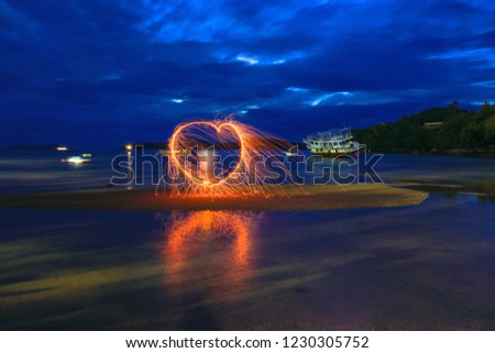 reflection of spark fire swirl from steel wool with long exposure speed motion abstract at sunrise in the sea

