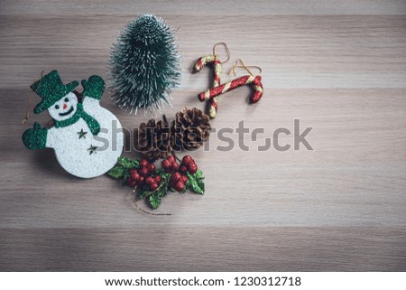 Cute snowman, tiny pine tree, pinecones, glitter holly berries arrange on wood board. Large copy space at right area for wording or pictures.