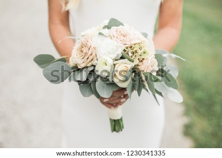 bride holding pastel wedding bouquet both hands, outdoor, romantic style