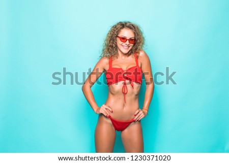 Positive beautiful young woman in bikini showing ok gesture isolated over green