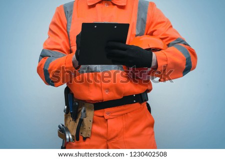 The measurer worker writes dimensions to his notebook. Building contract signing. Builder with construction project plans in the hands isolated on blue background.