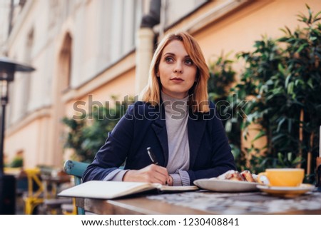 Shot of young woman sitting at a table and writing notes. Businesswoman working at her desk.
