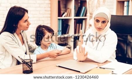 Arabic Doctor Refusing Bribes or Kickbacks, Money. Mom Giving to Doctor Money. Confident Muslim Female Doctor. Child at the Pediatrician. Hospital Concept. Healthy Concept. Patient Visiting Doctor.