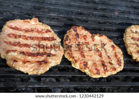 Grilling sausages, burgers, pork steak on barbecues gas grill for party. Hot dogs,sausages and hamburgers on a barbeque, bbq. Smokes meat food outdoors, fast food. Hamburgers. Pleskavitsa.