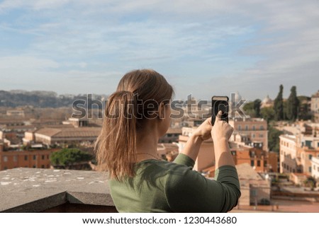 girl in green clothes takes photos with smartphone in Rome, Italy