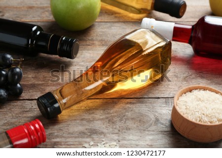 Bottles with different kinds of vinegar and ingredients on wooden table Royalty-Free Stock Photo #1230472177