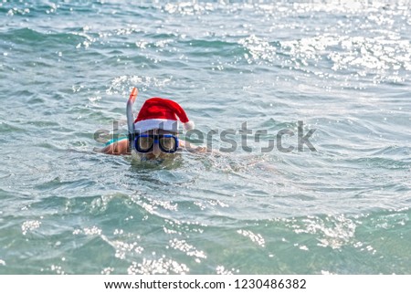 Man in a Santa Claus hat and diving mask, Christmas background with copy space. Relax in tropical countries in the winter, New Year's weekend.