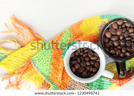 coffee beans in a cup wrapped in an autumn scarf / warming natural drink